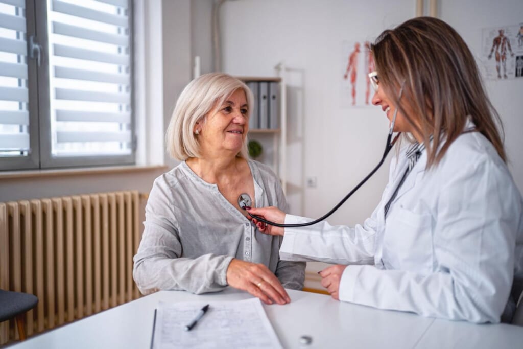 Beautiful doctor examines senior woman heartbeat at the doctor's office